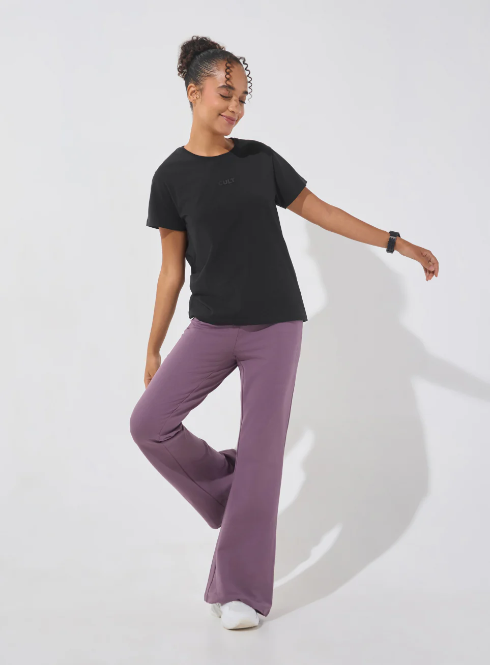 Model wearing a black performance T-shirt and purple trousers