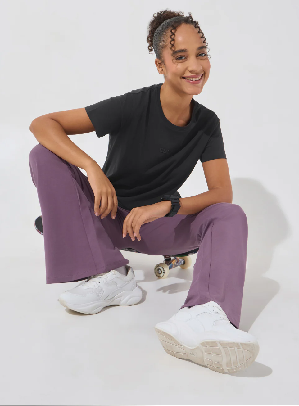 Model in a black T-shirt and purple trousers